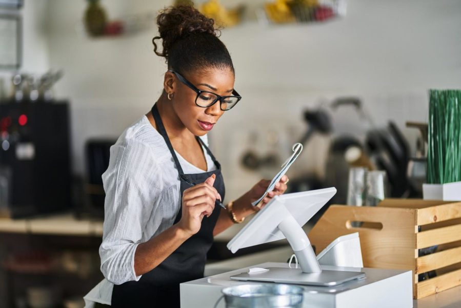 shop-assistant-placing-order-from-notepad-into-pos-point-of-sale-terminal-at-register-in-restaurant-2-1536x1025